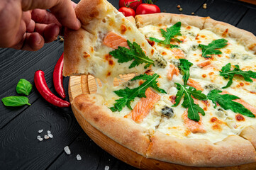 Sticker - Delicious hot pizza with salmon, arugula and different spices on wooden table ready to eat