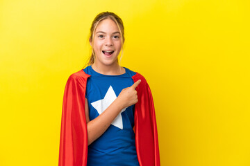 Wall Mural - Super Hero little girl isolated on yellow background surprised and pointing side