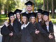 © Михаил Решетников - Group of happy graduates in robes outdoors.