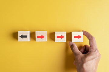 Fototapete - Hand holding woodblock Red arrow and different direction facing opposite direction with black arrow for business disruption and technology transformation and different thinking idea concept.