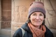 © Robert MEYNER - Group portrait photography of a pleased woman in her 50s wearing a warm beanie or knit hat against an ancient egyptian or hieroglyphics background. Generative AI