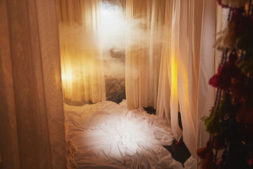 Light, soft transparent curtains in room. Canopy around bed with gentle light and blurring in evening. Boudoir. Concept of comfort in house and bedroom. Location and background for photo shoot