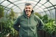 Pet portrait photography of a grinning man in his 50s wearing a comfortable tracksuit against a greenhouse or glasshouse background. Generative AI