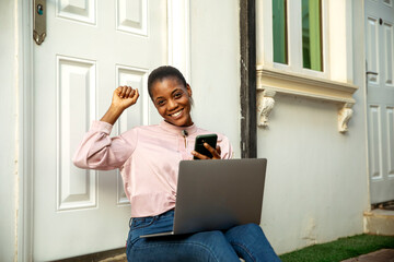 cheerful black woman using phone to make online purchases