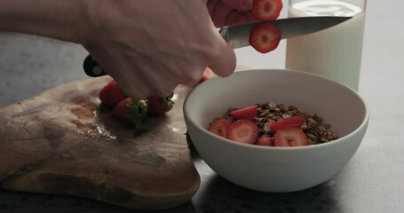 Wall Mural - Slow motion closeup man hands slicing fresh strawberries into chocolate granola