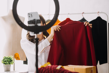 Fashion designer l young asian woman working using laptop, tablet and smiling while standing in workshop Responding on business