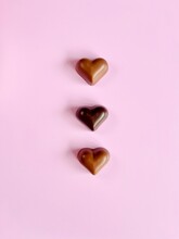 Overhead View Of Milk And Dark Chocolate Hearts On A Pink Background