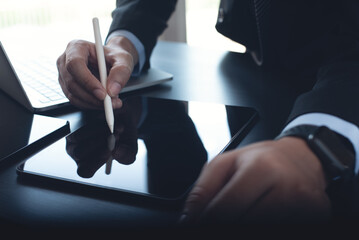 Canvas Print - Businessman using stylus pen on digital tablet with laptop computer, working in modern office, close up. Business man signing contract on tablet pc via mobile apps. electronic signature concept