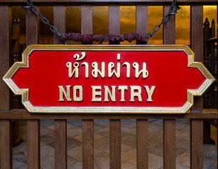 Close-up of a red sign with the text NO ENTRY in English and Thai, in the Wat Pho temple in Bangkok, Thailand.