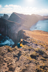 Wall Mural - Top angle view of a backpacker woman walking down from the windy foothills of an island in the Atlantic Ocean. São Lourenço, Madeira Island, Portugal, Europe.