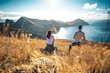 © Michael - Back view of a tourist couple on a hill, overlooking the coastal landscape of Madeira Island in the Atlantic Ocean in the morning. São Lourenço, Madeira Island, Portugal, Europe.