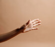 © Boadicea - Female hand on beige background. AI generated image.