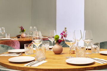 Round wooden dining tables of a restaurant with glassware next to the dishes