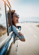 Happy, freedom and road trip with a woman in a car, looking at the view from the window while on the open road. Smile, travel and fun with a young female traveler on a journey during her vacation