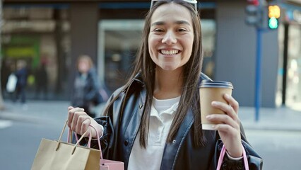 Wall Mural - Young beautiful hispanic woman smiling confident holding shopping bags and coffee at street