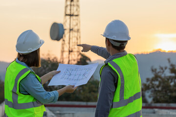 Professional team Engineer managers workers working outdoors with telecommunication antenna and sunset background.
