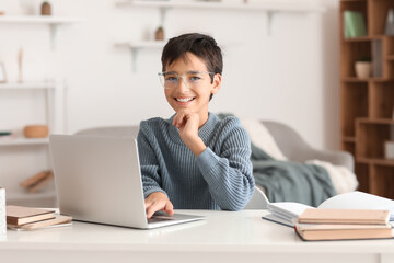 Wall Mural - Little boy in eyeglasses using laptop at home