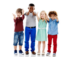 Wall Mural - Children, group and together for thumbs up in studio portrait with smile, agreement and white background. Girl, boy or isolated friends for happiness, hand like or solidarity for kids with diversity