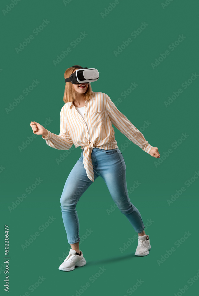 Pretty young woman in VR glasses on green background