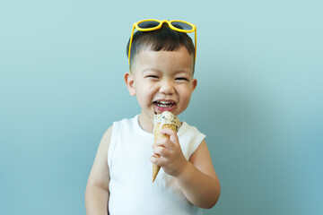 Portrait Cheerful Asian Japanese little boy eating ice cream on blue isolated background. Child boy having fun laughing.