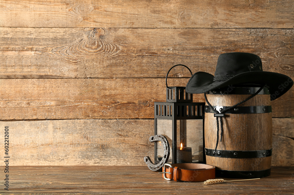 Composition with cowboy hat, belt and horseshoe on wooden background