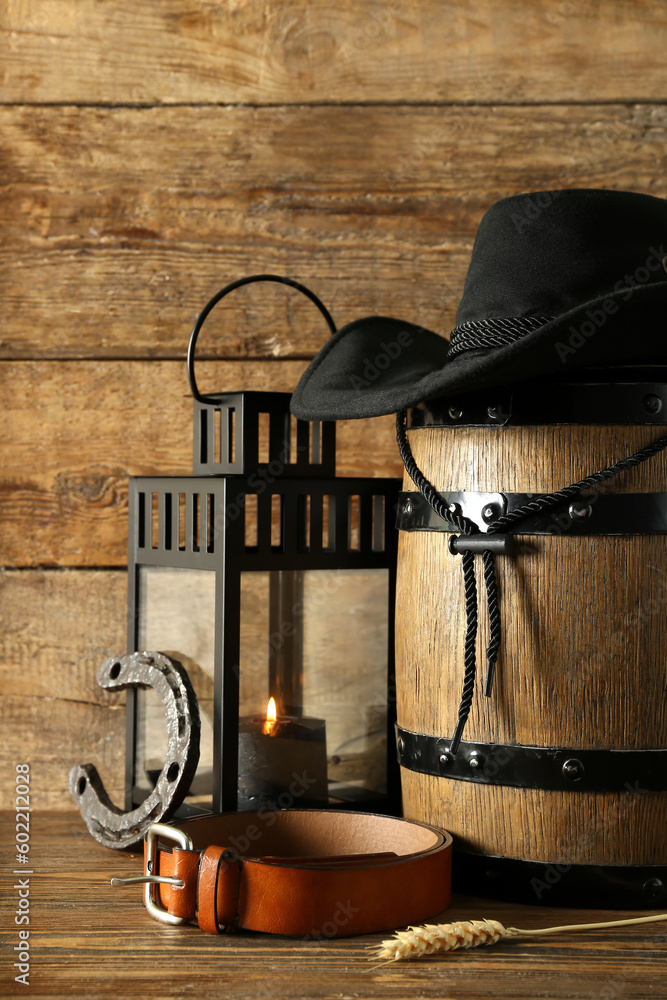 Composition with cowboy hat, belt and horseshoe on wooden background