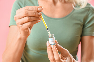 Wall Mural - Mature diabetic woman with syringe and insulin on pink background, closeup