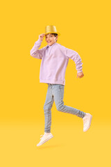 Wall Mural - Little boy in party hat jumping on yellow background. Children's Day celebration