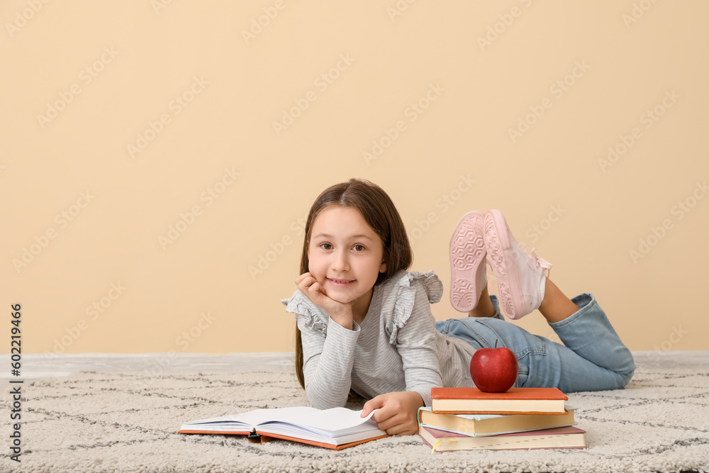 Little girl reading book near beige wall. Children's Day celebration
