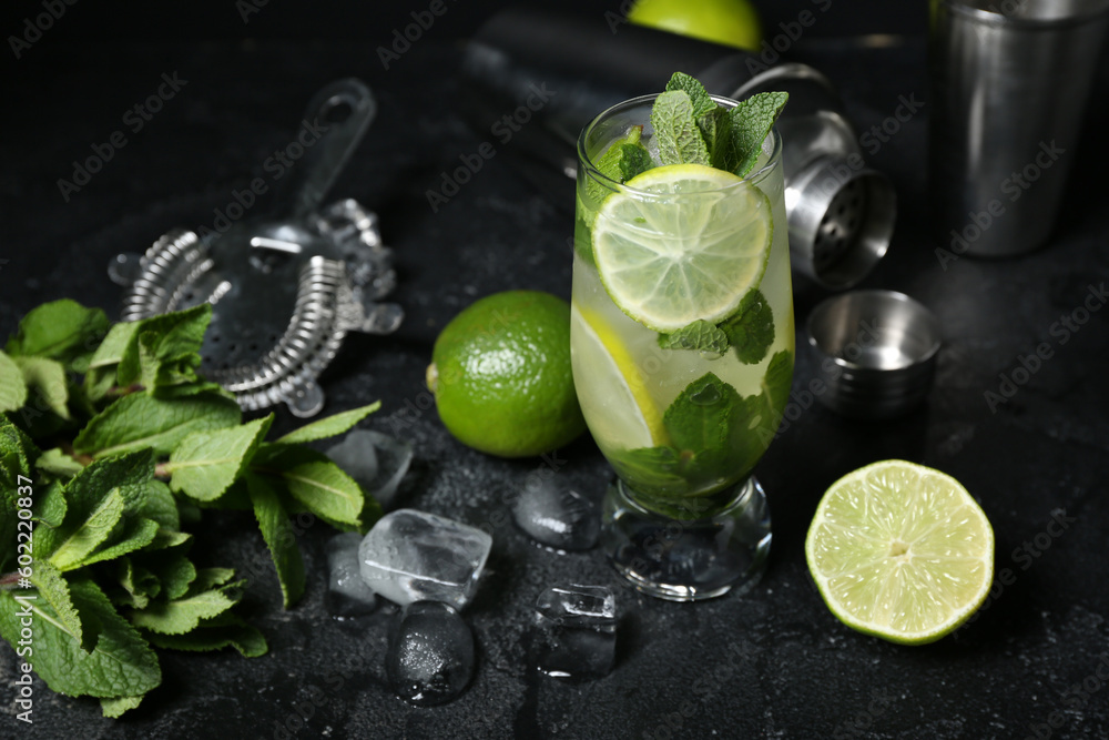 Glass of cold mojito and ingredients on dark background