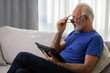 © Space_Cat - Senior man with glasses using digital tablet computer at home and having eyestrain or suffering from astigmatism and bad vision. Eyesight problems concept.