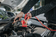 © Witoon - Close-up of auto mechanic charging car battery with electric rail jumper cables