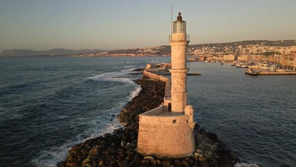 Wall Mural - Aerial circling camera view of a Venetian era lighthouse in golden sunset light (Chania)