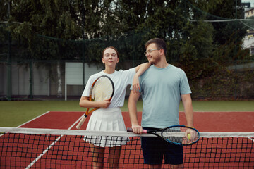 Happy Couple, tennis and sport portrait, training and exercise together outdoor, posing at tennis net on court.