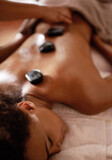 Hands, hot stone massage and woman in spa with luxury service for muscle, body and relax with peace in resort. Masseuse, hospitality and physical therapy on bed for wellness, zen and natural healing