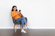 © Prostock-studio - Cheerful indian woman sitting in armchair, using cell phone