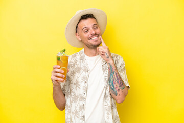 Wall Mural - Young caucasian man holding a cocktail isolated on yellow background thinking an idea while looking up