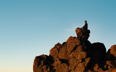 Man Sitting On Top Of Rock Cliff Meditating, Side View