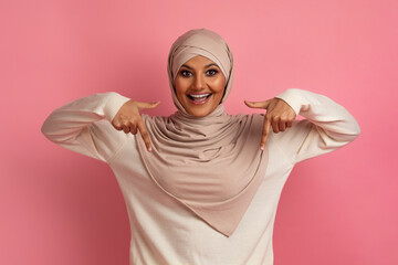 Look There. Excited muslim woman in hijab pointing down with two fingers