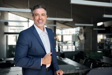 Happy middle aged business man ceo standing in office. Smiling mature confident professional executive manager, confident businessman leader wearing blue suit posing for corporate portrait.