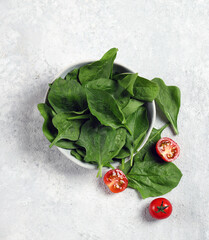 Wall Mural - fresh spinach in a gray plate on a light gray background top view