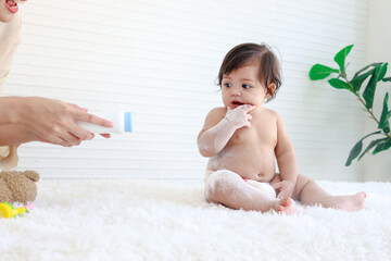 portrait of happy smiling toddle baby girl sit on fluffy white rug with mother hand hold dusting pow