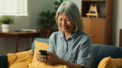 Wall Mural - Beautiful elderly woman using mobile phone playing social media checking email. Beautiful grandma hand holding smartphone waiting for text message from her family daughter, son, lonely face expression