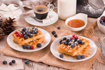 Wall Mural - Waffles with red currant and blueberries on white dish.