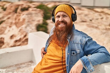 Wall Mural - Young redhead man smiling confident listening to music at street