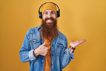 Canvas Print - Caucasian man with long beard listening to music using headphones showing palm hand and doing ok gesture with thumbs up, smiling happy and cheerful