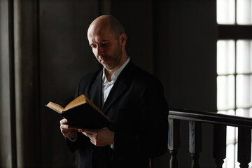 Canvas Print - Mature man in suit concentrating on reading Bible while praying in baptist church