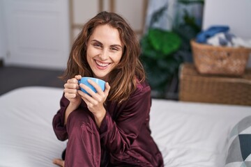 Canvas Print - Young woman drinking cup of coffee sitting on bed at bedroom