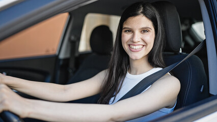 Wall Mural - Young beautiful hispanic woman smiling confident driving car at street