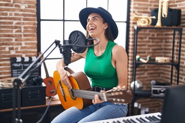 Sticker - Young hispanic woman musician singing song playing classical guitar at music studio